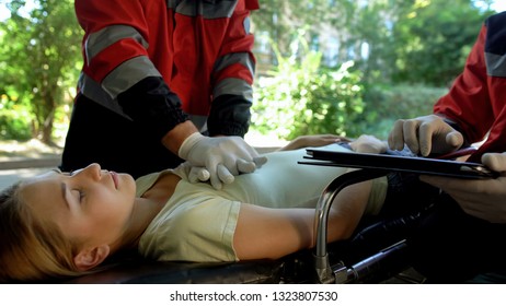 Male Paramedic Doing Indirect Heart Massage, Colleague Using Tablet For Records