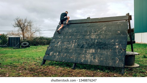 Male participant in an obstacle course climbing a pyramid obstacle - Powered by Shutterstock