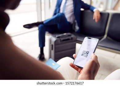 Male Passenger In Airport Departure Lounge Looking At Digital Boarding Pass On Smart Phone