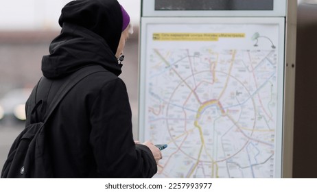 Male passenger analyzes transport card at a public transportation stop. Checking map and waiting for transport in city. Public transport route - Shutterstock ID 2257993977