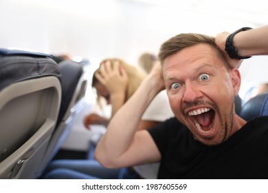 Male Passenger Holding His Head And Shouting On Plane