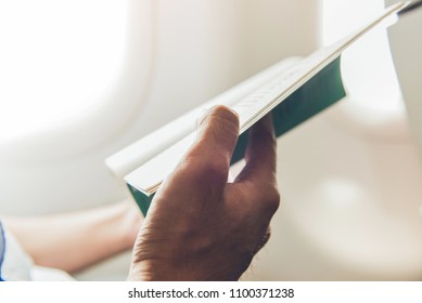 Male passenger killing time by reading book while traveling on the plane