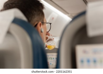 Male Passenger Relaxing On A Flight Drinking Beer On Board