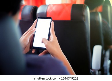 A Male Passenger Sitting In A Bus Seat Is Using His Phone