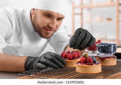 Male Pastry Chef Preparing Desserts At Table In Kitchen