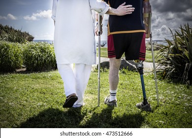 Male patient amputee wearing a prosthetic leg standing with a physiotherapist in a park, near the rehabilitation center - Powered by Shutterstock