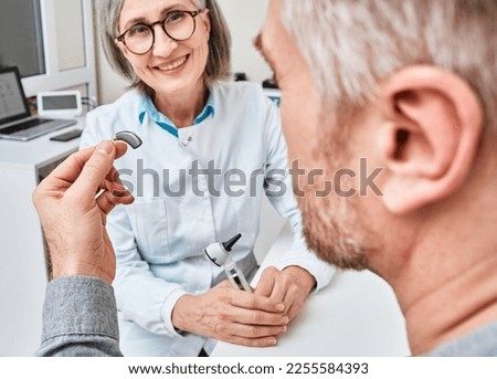 Male patient getting his hearing aid from audioprosthetist in audiology clinic. Hearing aids, hearing solutions
