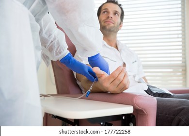 Male patient looking at nurse while receiving intravenous treatment in hospital room - Powered by Shutterstock