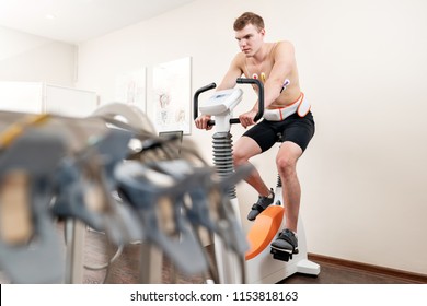 A Male Patient, Pedaling On A Bicycle Ergometer Stress Test System For The Function Of His Heart Checked. Athlete Does A Cardiac Stress Test In A Medical Study, Monitored By The Doctor.