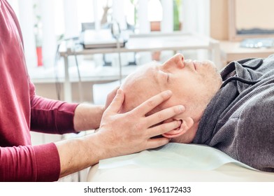 Male patient receiving cranial sacral therapy, lying on the massage table in CST ostheopatic treatment office, osteopathy and manual therapy