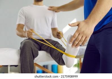 Male patient using elastic band while doing physical exercises for leg muscles at modern clinic, rehabilitation center or hospital. Close up of man's foot. Physiotherapy concept - Powered by Shutterstock