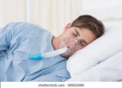 Male Patient Wearing Oxygen Mask Lying On Hospital Bed