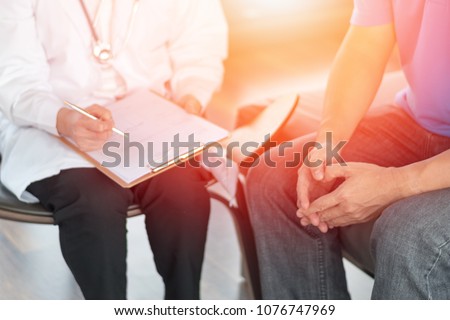 Male patients with psychologist holding client chart in psychotherapy session in hospital exam room. Men's health concept.