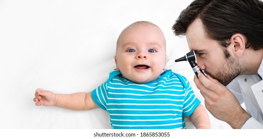 Male Pediatrician Examines Ear Infant Baby 3-month-old With An Otoscope. Child Receiving A Hearing Test