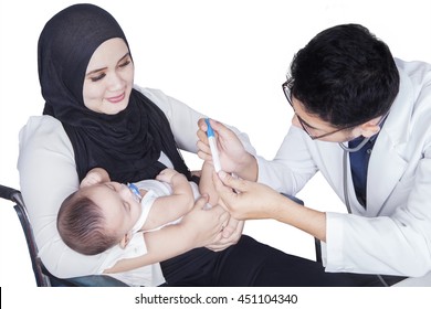 Male Pediatrician Examining A Newborn Baby While Talking With Young Mother Sitting On Wheelchair