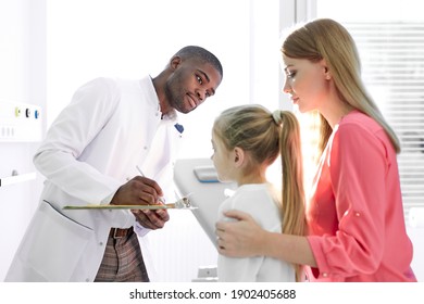 Male Pediatrician Explaining For Sick Child In Hospital Office, Healthcare Physician In Medicine Providing Health Care Services Treatment Examination For Caucasian Patients. Focus On Patients