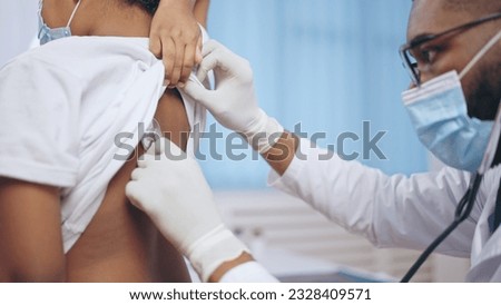 Male pediatrician listening to child's lungs with a stethoscope, pneumonia