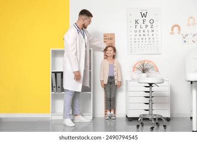 Male pediatrician measuring little girl's height in clinic - Powered by Shutterstock