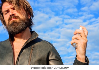 Male Perfumes, Cologne, Fragrance, Cosmetics. Bearded Man In Leather Jacket With Bottle Of Perfume.