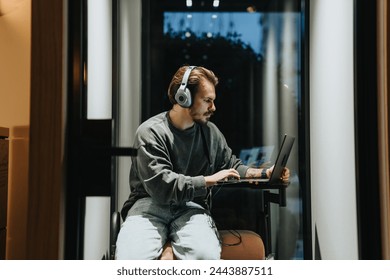Male person having video meeting call on his lap top at phone booth in the office.