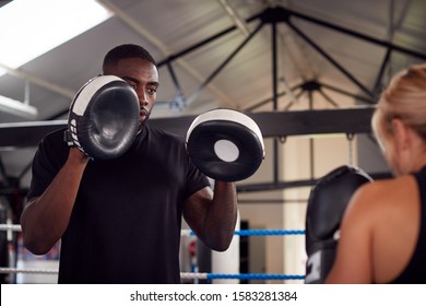 Male Personal Trainer Sparring With Female Boxer In Gym Using Training Gloves - Powered by Shutterstock