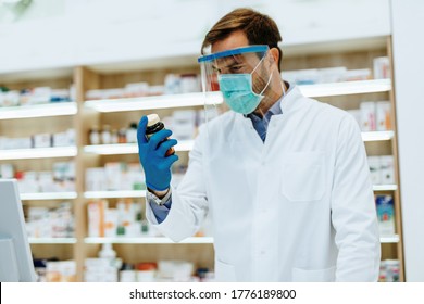 Male Pharmacist With Protective Mask And Face Shield On His Face, Working At Pharmacy. Medical Healthcare Concept.