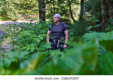 Male Photographer Hiking On A Trail In A Lush Forest With His Backpack