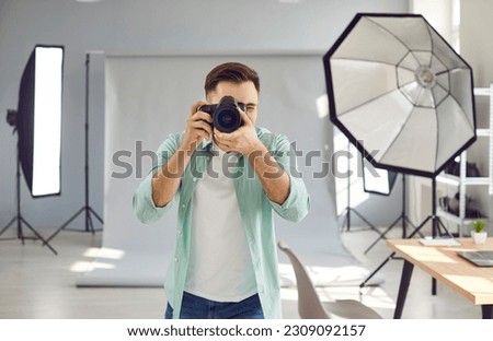 Male photographer shooting in studio with professional lighting equipment. Portrait of professional freelance photographer taking photo with professional digital camera