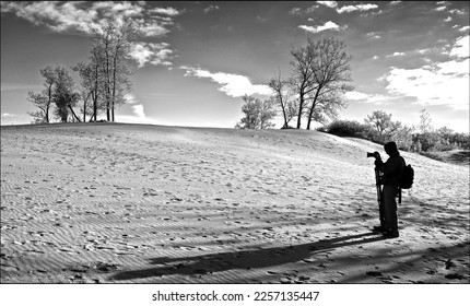 A male photographer taking photos on the sand dune