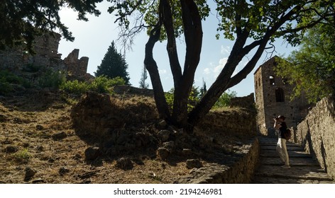 Male Photographer Taking Pictures Of Ancient City Of Mystras, Sparta. UNESCO World Heritage Archeological Sight.