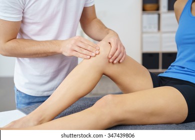 Male Physical Therapist Checking the Knee Condition of a Female Patient Sitting on the Bed.