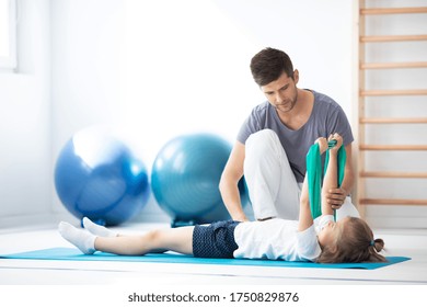 Male physical therapist exercising with little girl during rehabilitation