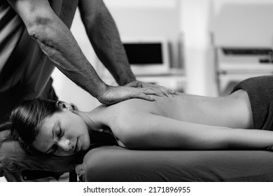 Male Physical Therapist Massaging Female Client’s Back Muscle.