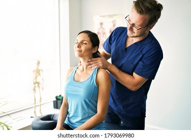 A Male Physical Therapist Stretching A Female Patient Neck