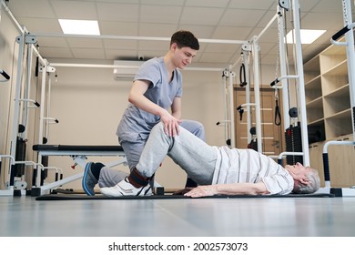 Male Physician Assisting Old Patient In His Leg Exercise