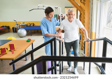 Male physiotherapist assisting elderly man in movement therapy at rehab center - Powered by Shutterstock