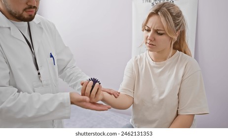 A male physiotherapist in a clinic assesses the arm of a female patient expressing discomfort. - Powered by Shutterstock