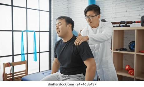 A male physiotherapist examines a patient's back in a clinic room. - Powered by Shutterstock