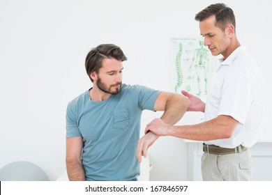 Male physiotherapist examining a young man's arm in the medical office