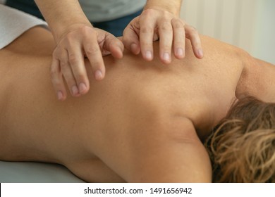 male physiotherapist manipulating on the back of a woman on the stretcher