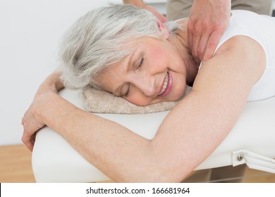 Male physiotherapist massaging a senior woman's shoulder in the medical office - Powered by Shutterstock