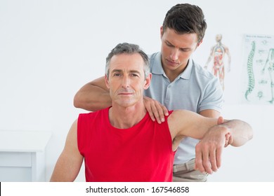 Male physiotherapist stretching a mature mans arm in the hospital