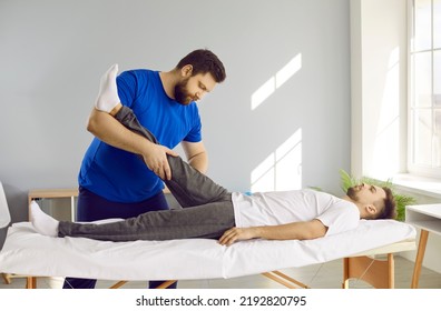 Male physiotherapist work patient after leg trauma help with pain relief and rehabilitation. Therapist or osteopath massage client leg after injury. Recovery and rehab center concept.