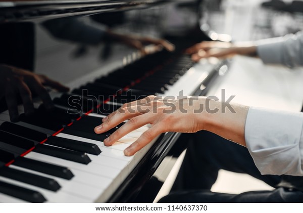 Male pianist hands\
on grand piano keyboard