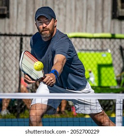 Male pickelball player reaches for the ball during a tournament - Shutterstock ID 2052700229