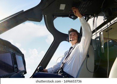 Male Pilot In Cockpit Of Helicopter Doing Pre Flight Check Before Take Off - Powered by Shutterstock