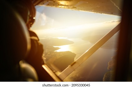 Male pilot are cooperating during flight on a small aircraft. Small single engine airplane flying in the gorgeous sunset sky through the sea of clouds above the spectacular mountains
