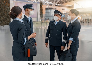 Male Pilots And Female Flight Attendants Talking In Airport Terminal