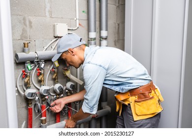 Male plumber checks pipes for central hot and cold water supply of apartment