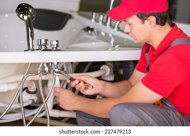 Male Plumber Fixing Sink Pipe In The Bathroom.